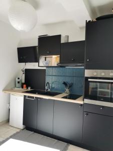 a kitchen with black and blue cabinets and a sink at Mèze, charmant petit studio proche port in Mèze