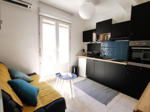 a living room with a couch and a kitchen at Mèze, charmant petit studio proche port in Mèze