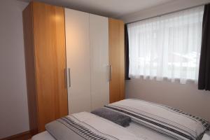 ガシュルンにあるAppartement Bergzeitのベッドルーム1室(ベッド1台、キャビネット、窓付)