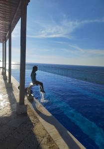uma pessoa sentada à beira de uma piscina de água em AZ Apartments em Cartagena das Índias