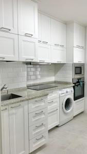 a kitchen with white cabinets and a washing machine at APARTAMENTO en MUNDAKA con GARAJE in Mundaka