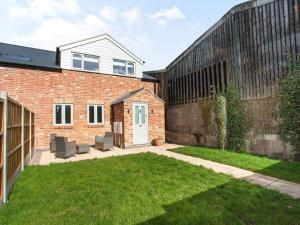 a brick house with a lawn in front of it at Brick Kiln Cottage in Burton Overy