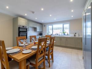 cocina y comedor con mesa de madera y sillas en Brick Kiln Cottage en Burton Overy