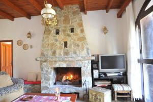 a living room with a stone fireplace and a tv at CASA IRENE in Kakopetria