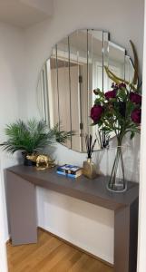 a table with flowers on it with a mirror at The Reflection Apartment , With river Thames view in North Woolwich