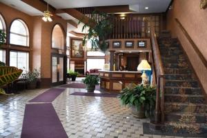 ein Gebäude mit einer Lobby mit Treppen und einem Zimmer mit Pflanzen in der Unterkunft Hamilton Inn Select Beachfront in Mackinaw City