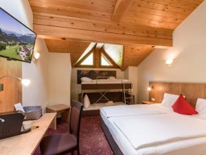 a hotel room with two beds and a desk and a tv at Alpengasthof Gruberhof in Söll