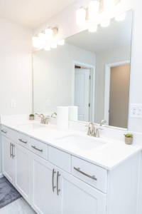 a white bathroom with two sinks and a large mirror at New spacious 3 bedroom suite garage parking free Wi-Fi office space and patio view in Duluth