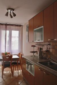 cocina con armarios de madera, mesa y comedor en Delux apartment Moj Osijek, SELF CHECK-IN, en Osijek