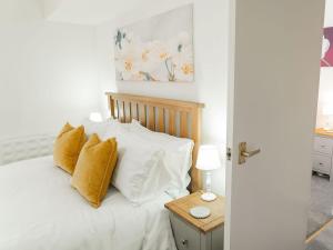 a bedroom with a bed with white sheets and yellow pillows at White Hart Cottage in Ulverston