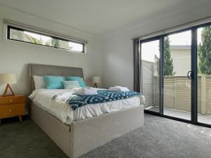 a bedroom with a bed with blue pillows and a window at Bliss on the Bay Cheerful townhouse in Torquay in Torquay