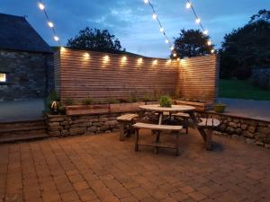 a patio with a table and a fence with lights at Hawks Barn in Horton in Ribblesdale