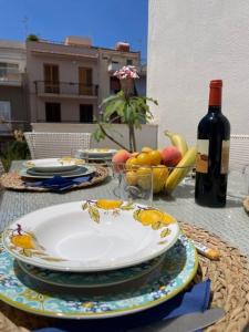 奇尼斯的住宿－GUEST HOUSE ZIO MICHELE - CINISI，一张桌子,上面放着一盘水果和一瓶葡萄酒
