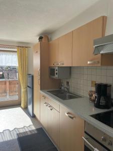 a kitchen with wooden cabinets and a sink and a window at Ferienwohnung Rauch in Schwendau