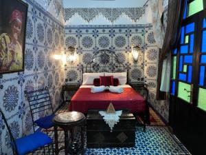 a bedroom with a bed with red sheets and blue and white tiles at DAR EL AAMOURI in Fez