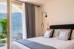 a bedroom with a bed and a large window at Villa Mojana Bellagio in Oliveto Lario