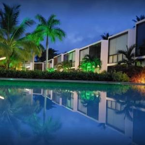 un edificio con palmeras frente a una piscina en Barra Grande Pe na Areia Beira Mar en Barra Grande