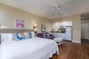 a bedroom with a white bed and a kitchen at Harbour House at the Inn 314 in Fort Myers Beach
