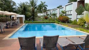 a swimming pool at a resort with chairs and tables at Barra Grande Pe na Areia Beira Mar in Barra Grande