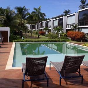 a swimming pool with two chairs in front of a building at Barra Grande Pe na Areia Beira Mar in Barra Grande