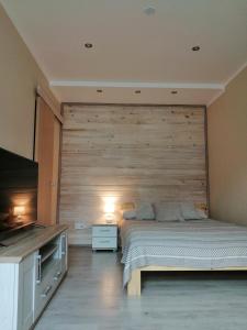 ein Schlafzimmer mit einem Bett und einer Holzwand in der Unterkunft Apartamenti Miera Osta in Liepāja
