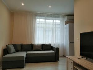 a living room with a couch and a window at Apartamenti Miera Osta in Liepāja