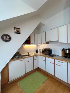 a kitchen with white cabinets and a green rug at Cosy apartment in central location in Vienna