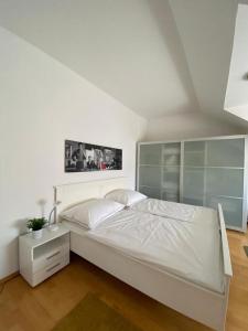 a white bedroom with a bed and a night stand at Cosy apartment in central location in Vienna