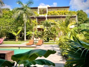 un complejo con piscina y palmeras en XscapeTulum, en Tulum