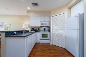 a kitchen with white cabinets and a white refrigerator at Harbour House at the Inn 214 in Fort Myers Beach