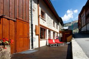 two red chairs sitting on a wooden deck next to a building at Chalet Ruby in Les Deux Alpes