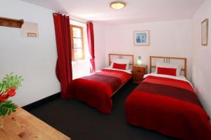 two beds in a room with red curtains at Chalet Ruby in Les Deux Alpes