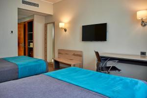 a hotel room with two beds and a desk and a television at Hotel Diego de Almagro Talca Express in Talca