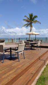 a wooden deck with tables and chairs on the beach at Barra Grande Pe na Areia Beira Mar in Barra Grande