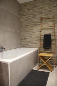 baño con bañera blanca y escalera de madera en Charmante maison de campagne "Chemin Saint-Roch", 