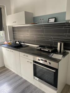 eine Küche mit weißen Schränken und einem Herd mit Backofen in der Unterkunft estrella24 LIVING ROOMS London in Herne