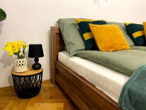 a bed with green and yellow pillows and a table with a lamp at Green House apartments in Krakow