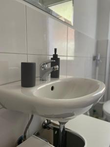 La salle de bains est pourvue d'un lavabo blanc et d'un miroir. dans l'établissement estrella24 LIVING ROOMS London, à Herne