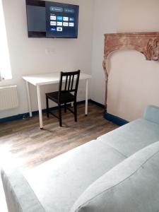 a bedroom with a table and a chair and a tv at Le JOËL appartement F1 de 21 m² in Choisey