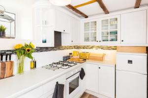 a white kitchen with white cabinets and a vase of flowers at Why Not in Stow on the Wold