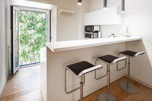 uma cozinha com dois bancos num balcão com um lavatório em Brera Livings, Charming flat near Duomo em Milão