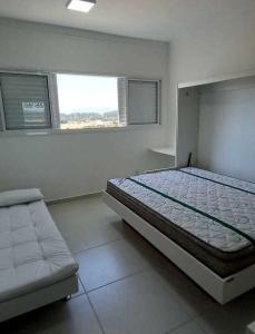 een witte slaapkamer met een bed en een bank bij Loft - Condomínio da Fé - Canção Nova in Cachoeira Paulista