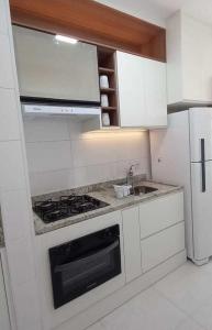 een keuken met een fornuis, een wastafel en een koelkast bij Loft - Condomínio da Fé - Canção Nova in Cachoeira Paulista