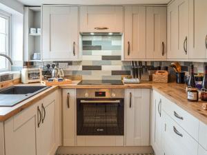 a kitchen with white cabinets and an oven at Fox Cottage in Henstead