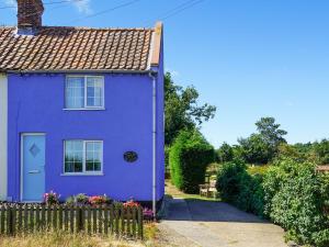 a purple house with a fence in front of it at Fox Cottage in Henstead