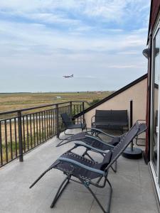uma varanda com cadeiras e um avião voando no céu em Airport Gate 25 em Ledine