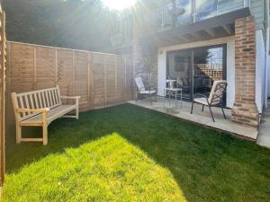 a patio with a bench and chairs on a lawn at Little Crickets in Felpham