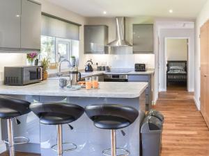 a kitchen with a large island with black bar stools at Park View in Martham
