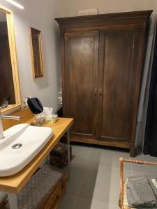 a bathroom with a sink and a wooden cabinet at Suite privée avec accès jardin en coeur de village 