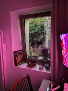 Habitación rosa con ventana, mesa y escritorio. en Suite privée avec accès jardin en coeur de village 